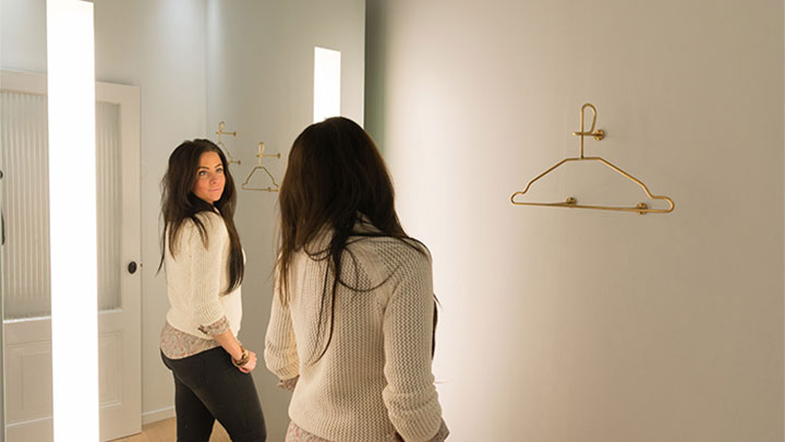 O clientă SuperTrash privindu-se în oglinda AmbiScene de la Philips, cu setarea de lumină „Zi”