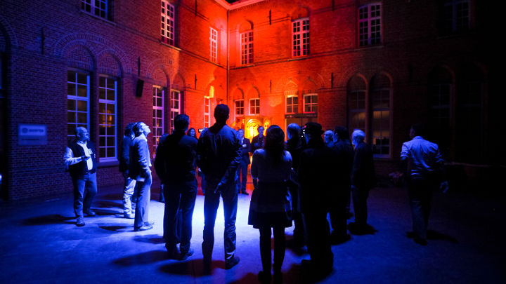 Un grup mare de persoane discută în faţa unei clădiri iluminate frumos din Turnhout, Belgia, cu ocazia unui atelier organizat de Philips
