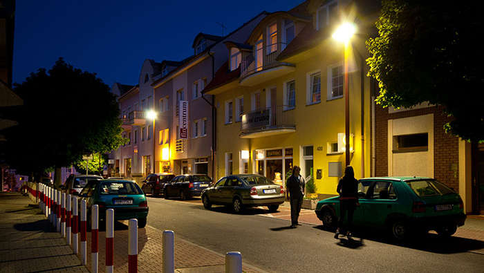 Oamenii merg pe stradă noaptea protejaţi de iluminatul stradal de la Philips 