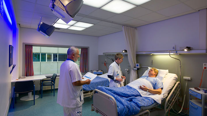 Doctori îngrijind un pacient într-un salon iluminat cu sistemul Healwell de la Philips