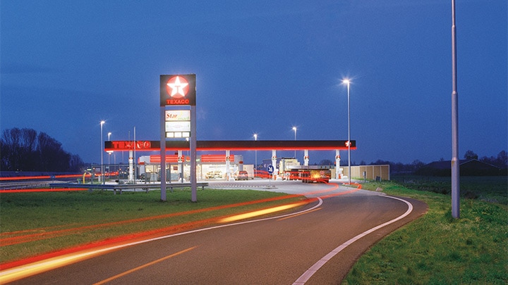 O benzinărie Texaco lângă o autostradă, iluminată plăcut la asfințit – un iluminat exterior care atrage privirea